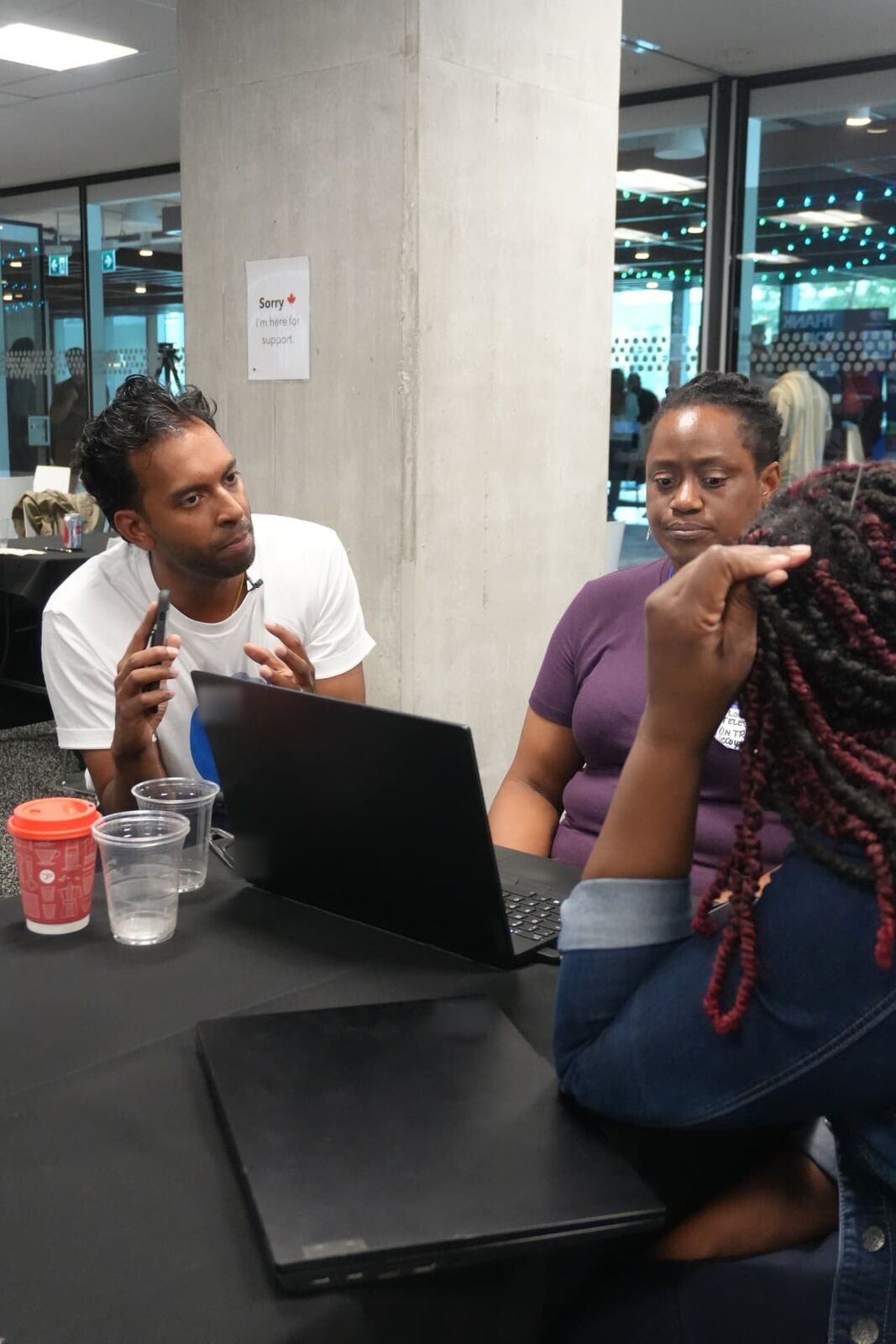 Accountants comparing their work around a laptop at the Toronto Claude workshop